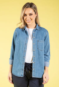 Woman wearing a denim shirt over a white top on a yellow background