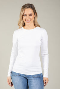 Woman wearing a white long-sleeve top and blue jeans against a plain background