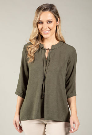 Woman wearing an olive green blouse with a neutral background