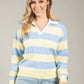 Woman wearing a blue and yellow striped sweater against a gray background