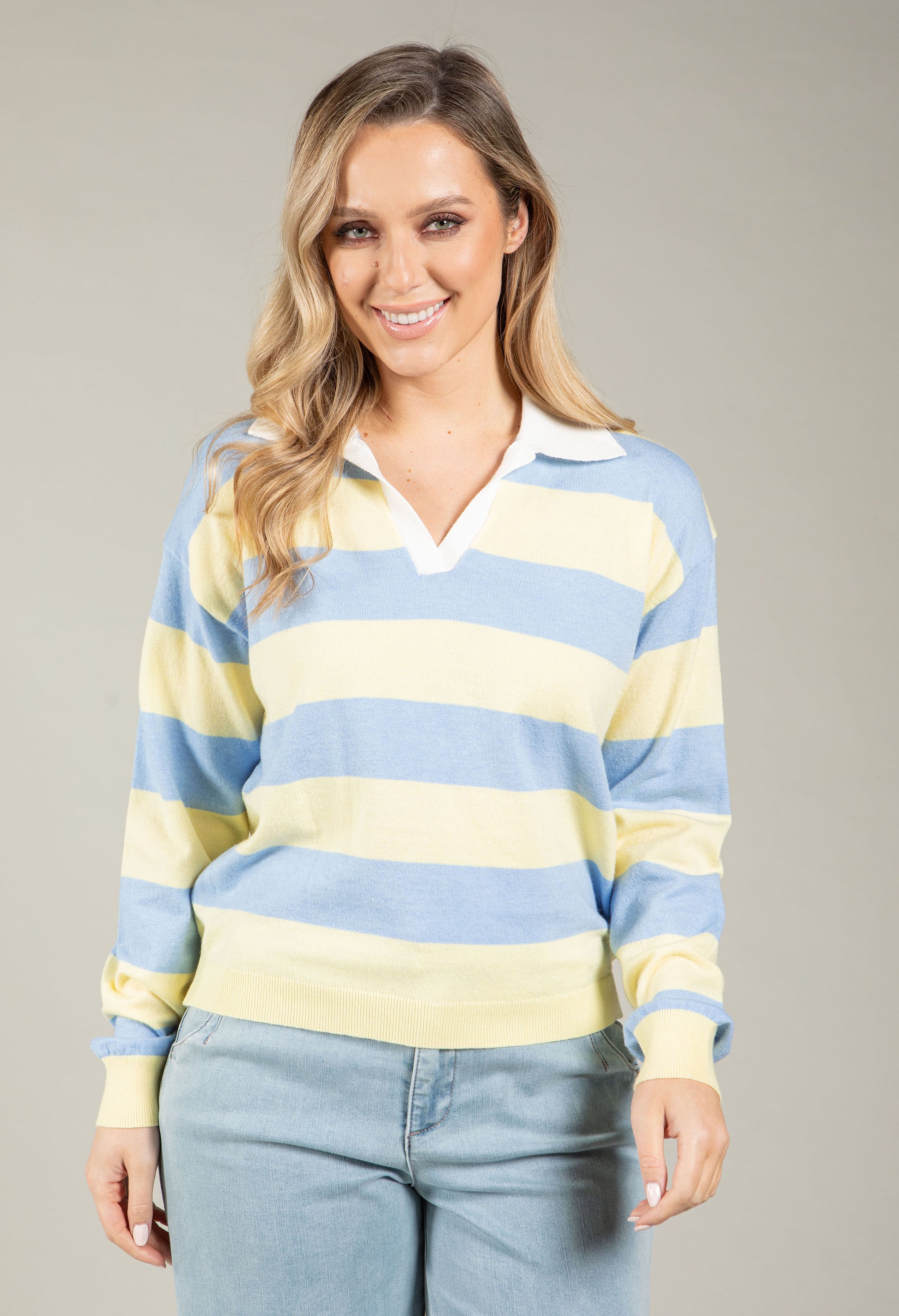 Woman wearing a blue and yellow striped sweater against a gray background