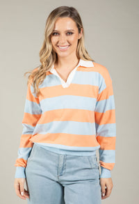 Woman wearing a striped sweater with orange and blue horizontal stripes on a plain background