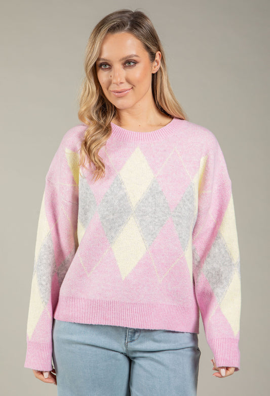 Woman wearing a pastel argyle sweater against a neutral background