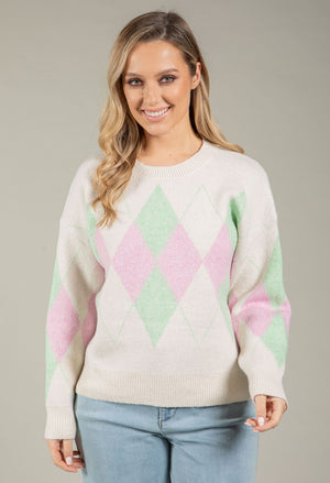 Woman wearing a pastel argyle sweater against a neutral background