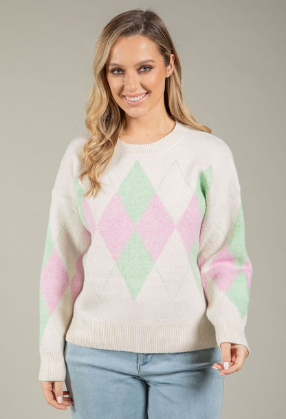 Woman wearing a pastel argyle sweater against a neutral background