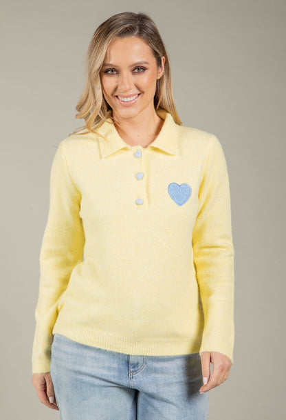 Woman wearing a yellow sweater with a blue heart design on a gray background