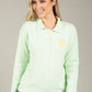 Woman wearing a light green sweater with a heart design on a gray background