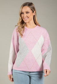 Woman wearing a pink and gray patterned sweater against a plain background