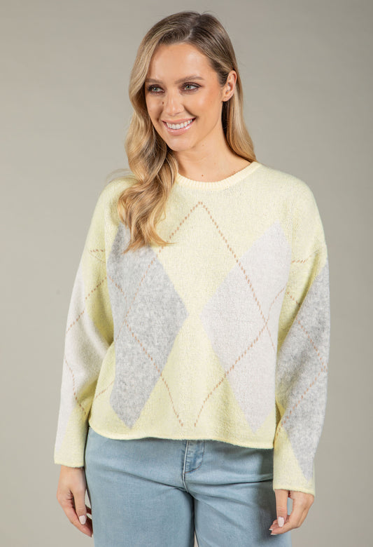 Woman wearing a light blue and gray diamond pattern sweater against a neutral background