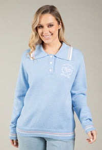 Woman wearing a light blue sweater with white collar and trim on a gray background