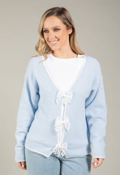 Woman wearing a light blue sweater with lace details on a plain background