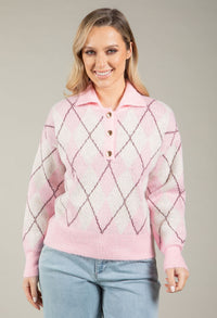 Woman wearing a pink diamond pattern sweater against a neutral background