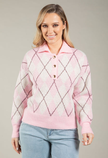 Woman wearing a pink diamond pattern sweater against a neutral background