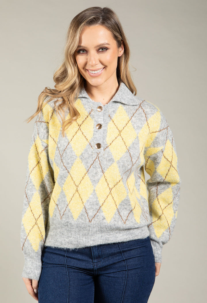 Woman wearing a gray and yellow argyle sweater against a plain background