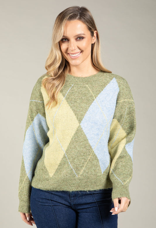 Woman wearing a green sweater with geometric pattern on a beige background