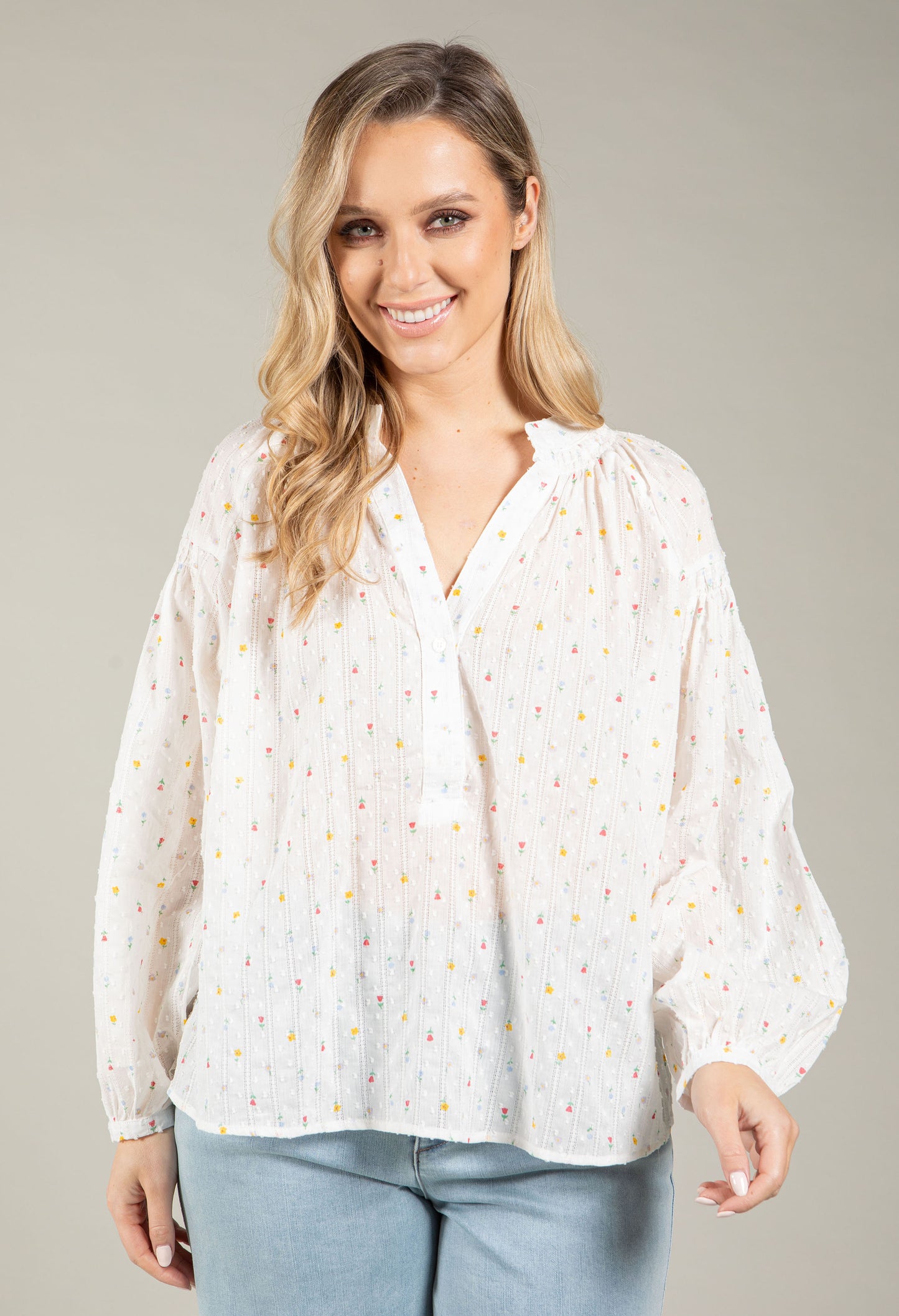 Woman wearing a white blouse with small patterns on a plain background
