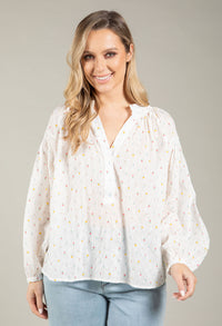 Woman wearing a white blouse with small patterns on a plain background