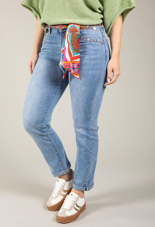 Person wearing blue jeans with a colorful bandana around the waist on a neutral background