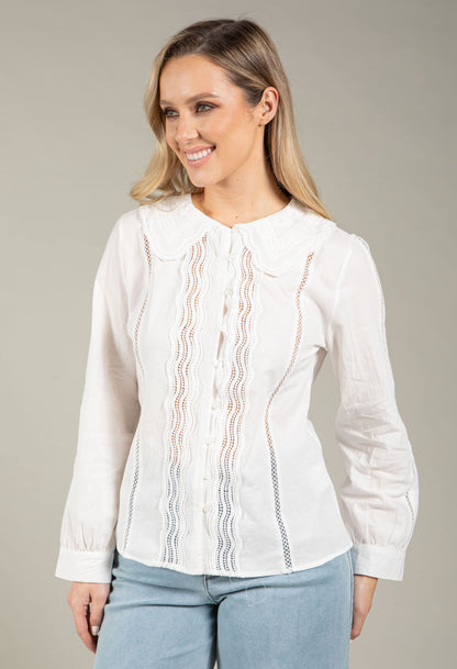 Woman wearing a white blouse with lace details on a gray background