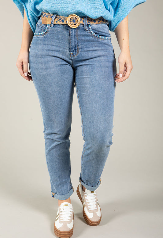 Person wearing blue jeans and a light blue top on a plain background