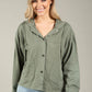 Woman wearing an olive green jacket against a plain background
