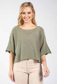 Woman wearing a green sweater and beige pants on a white background