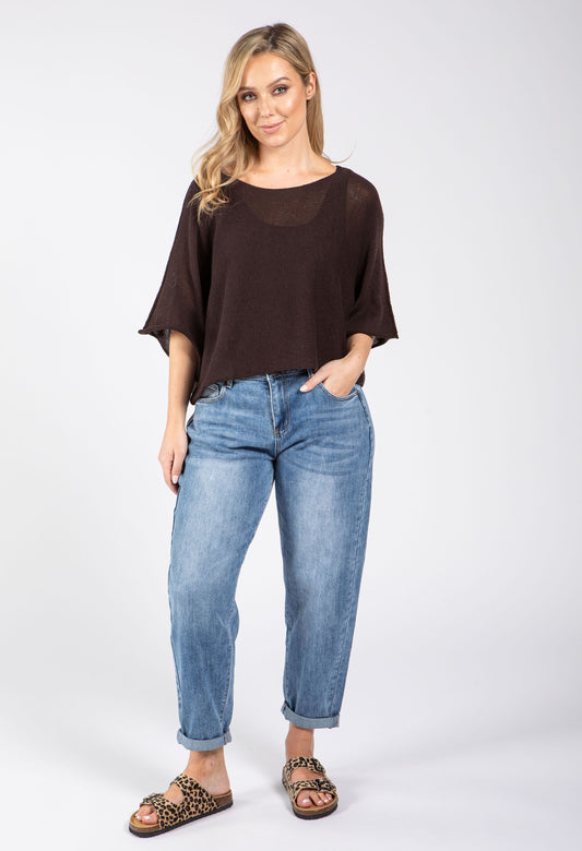 Woman wearing a beige top and dark blue pants on a white background