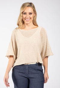 Woman wearing a beige top and dark blue pants on a white background