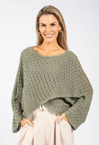 Woman wearing a green poncho against a white background