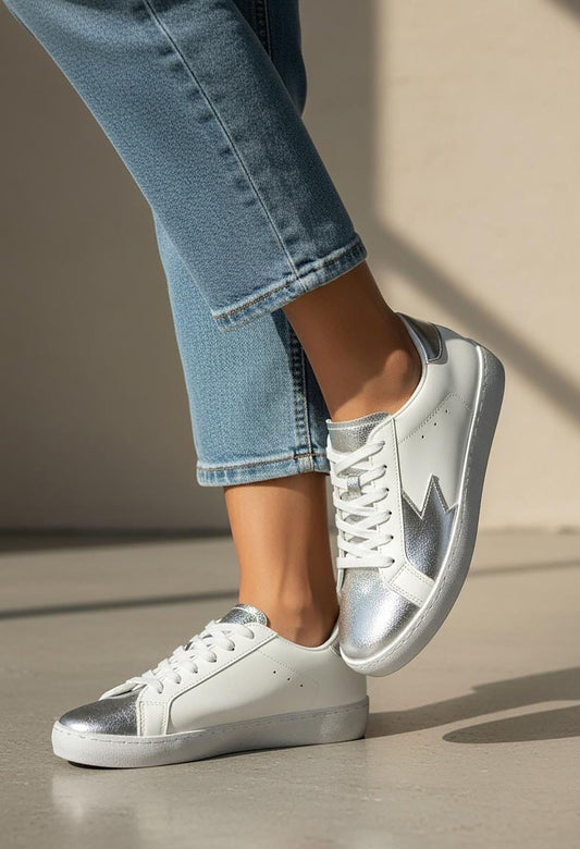 White sneakers with gold soles worn by a person on a neutral background