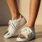 White sneakers with gold soles worn by a person on a neutral background