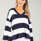 Woman wearing a navy and white striped sweater against a gray background