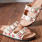 Cream sandals with embroidered cherry design, double straps and gold buckles