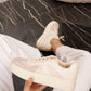 White sneakers being held on a marble floor