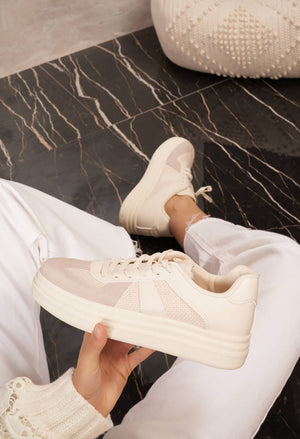 White sneakers being held on a marble floor