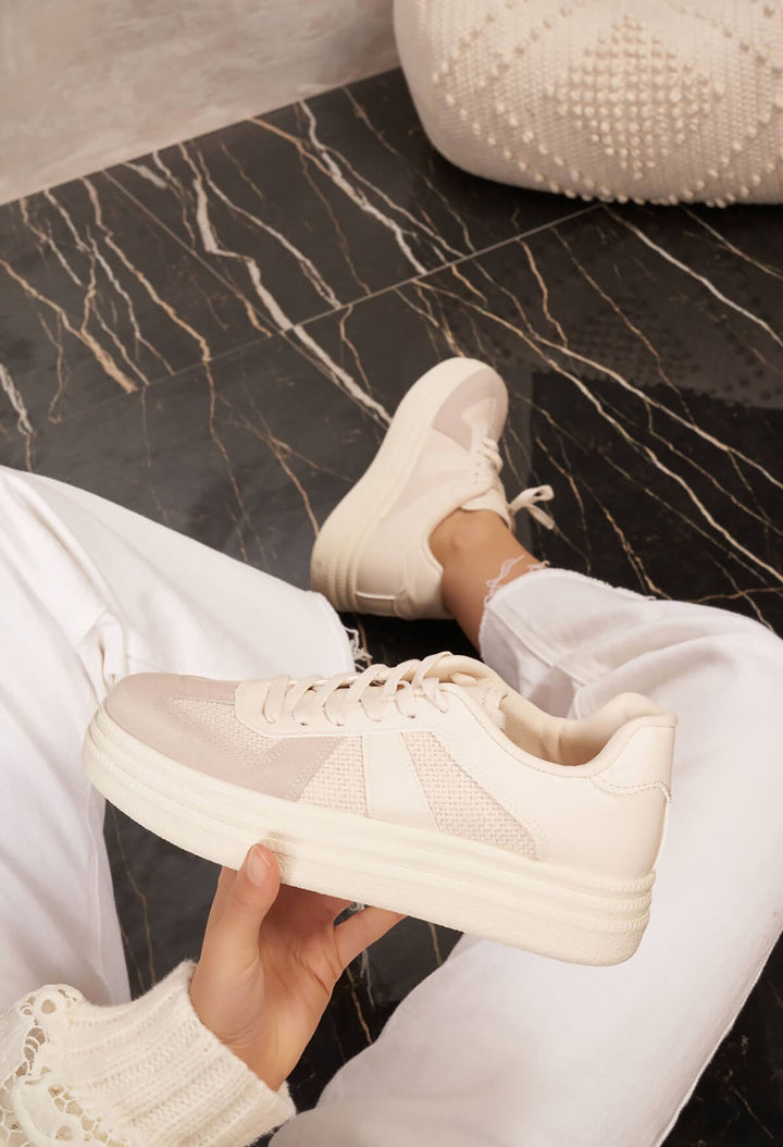 White sneakers being held on a marble floor