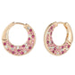 Pair of gold hoop earrings with pink gemstones on a white background