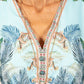Close-up of a colorful dress with floral and palm tree patterns.