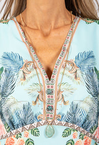 Close-up of a colorful dress with floral and palm tree patterns.