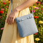 Person holding a blue textured handbag with a floral background