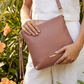 Person holding a pink handbag with a blurred natural background