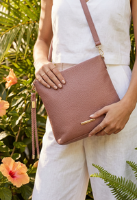 Person holding a pink handbag with a blurred natural background