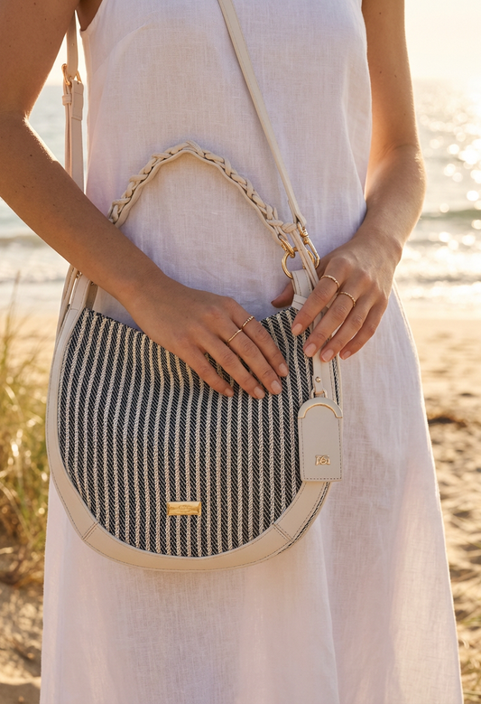 Person holding a striped handbag with a blurred natural background