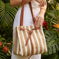 Person holding a striped handbag with a tropical background