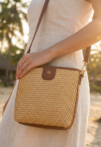 Person holding a woven handbag with a blurred natural background
