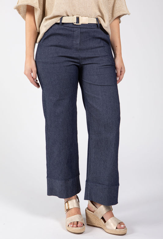 Person wearing navy blue pants with a beige top on a white background