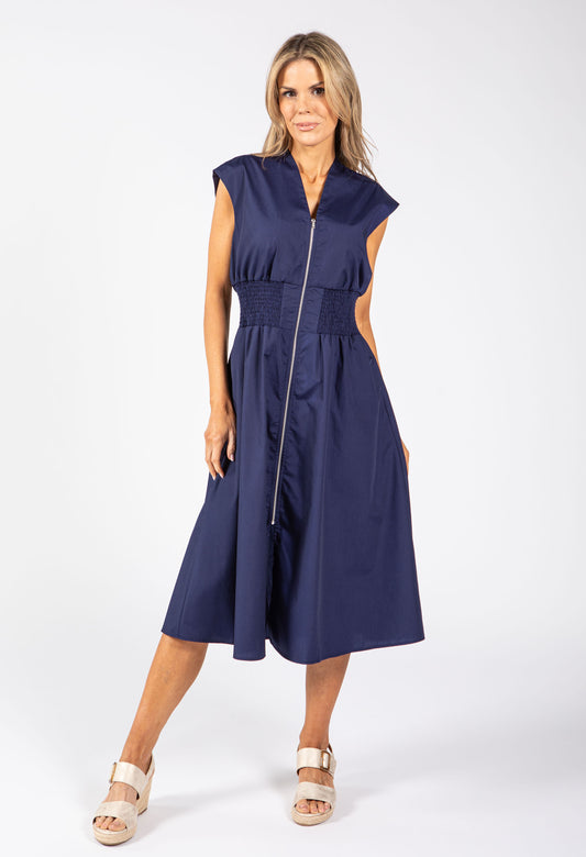 Woman in a navy dress holding a red and white striped bag on a white background