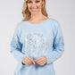 Woman wearing a light blue sweater with lace details on a white background