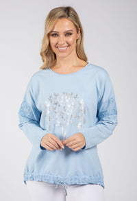 Woman wearing a light blue sweater with lace details on a white background