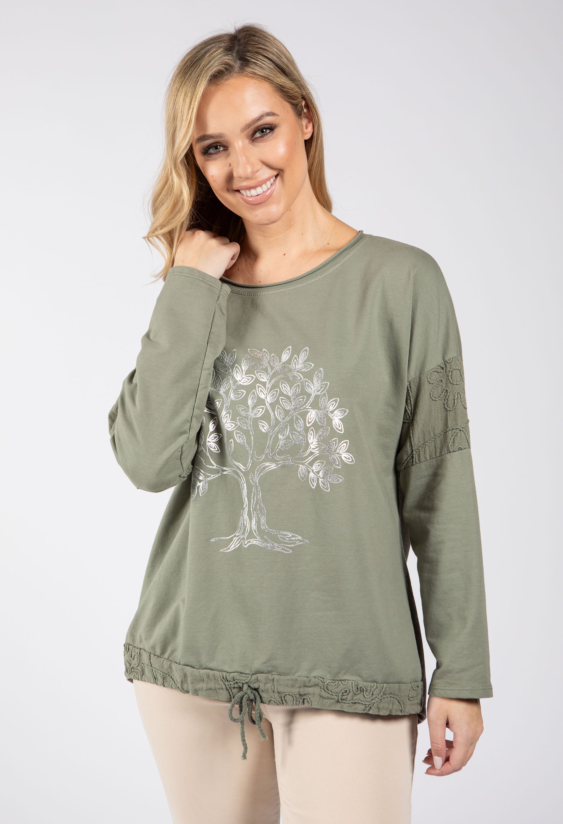 Woman wearing an olive green long-sleeve top with a tree design on a white background